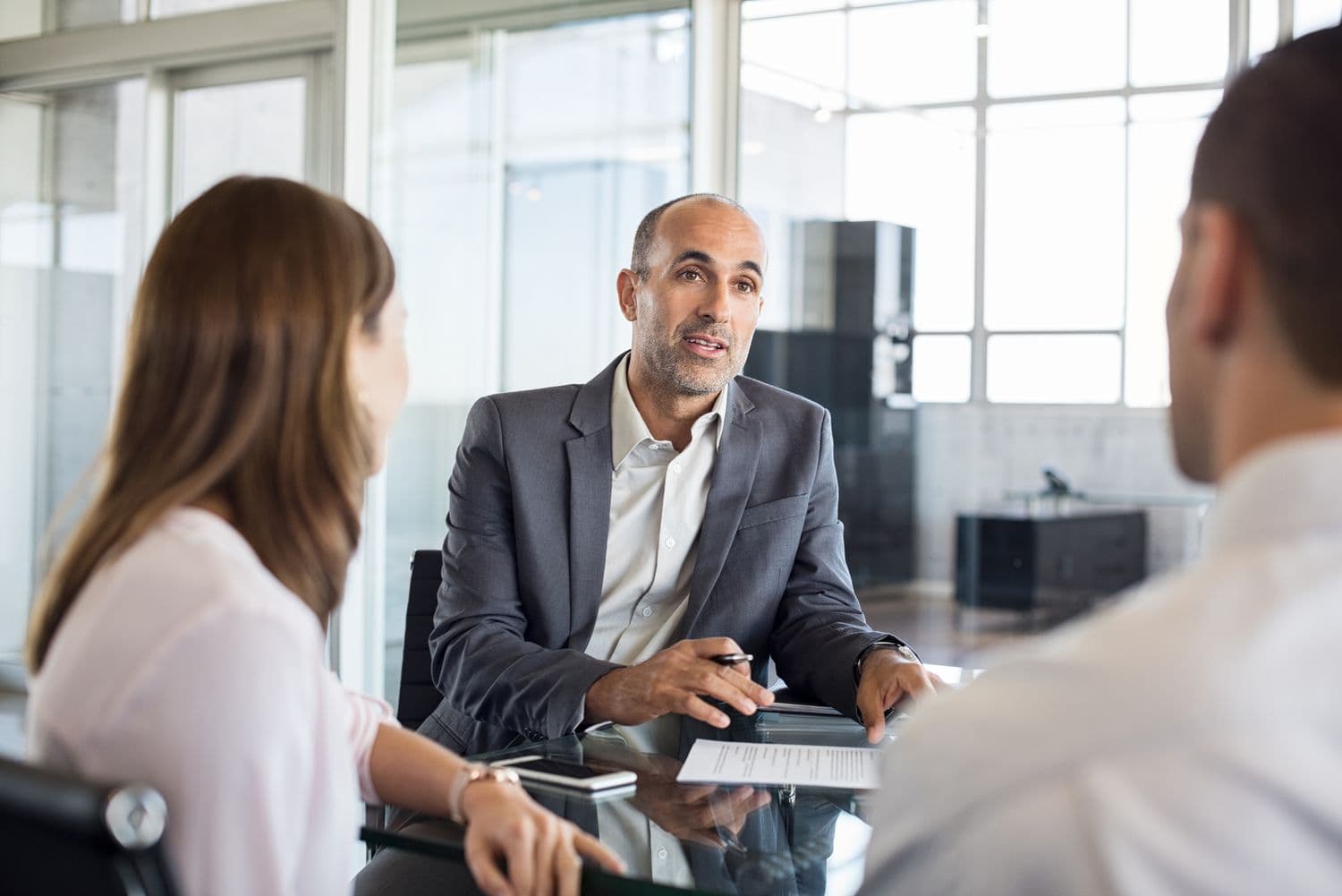 Businessman talking to a man and a woman at a table