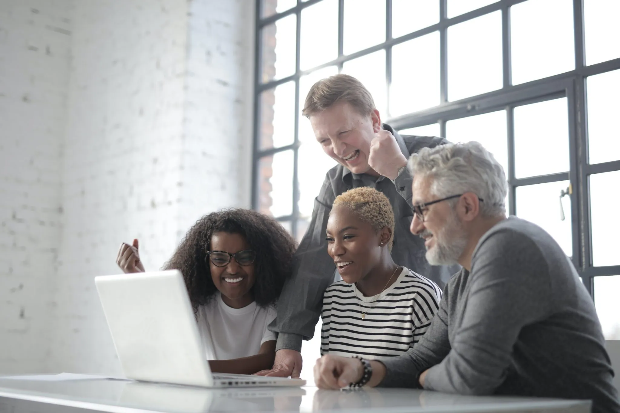 4 people at a desk looking at a laptop