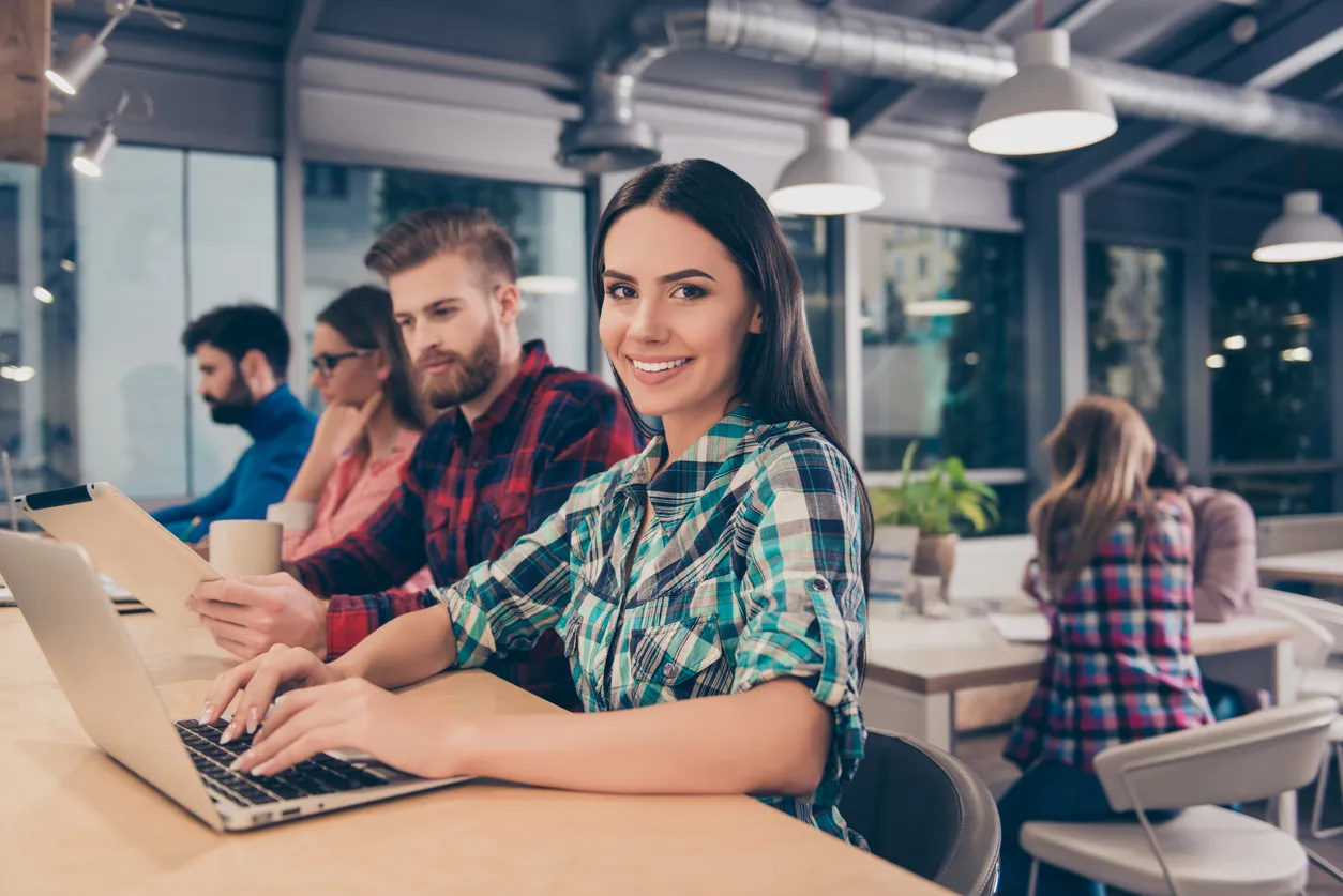 Woman working at a counter in a shared workspace tying on a laptop