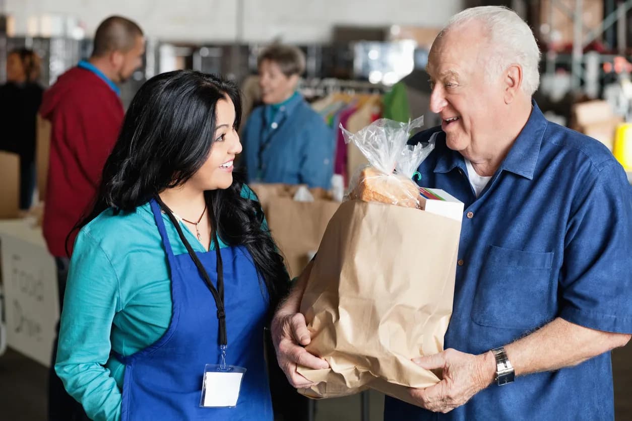 Man carrying grocery bag talking to female grocery store employee